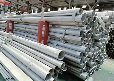 A stack of stainless steel pipes organized in a warehouse.